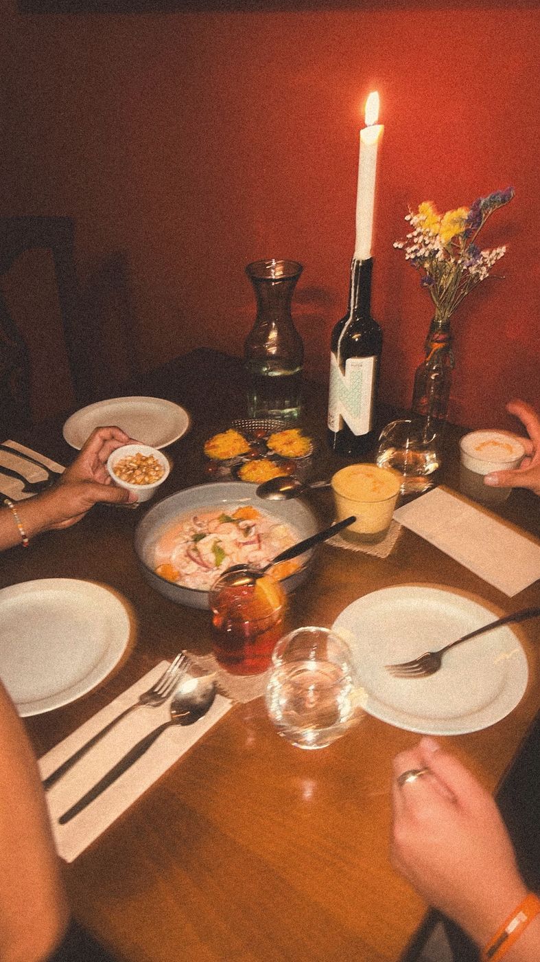 Mesa con ceviche, cancha, pisco sour y vela