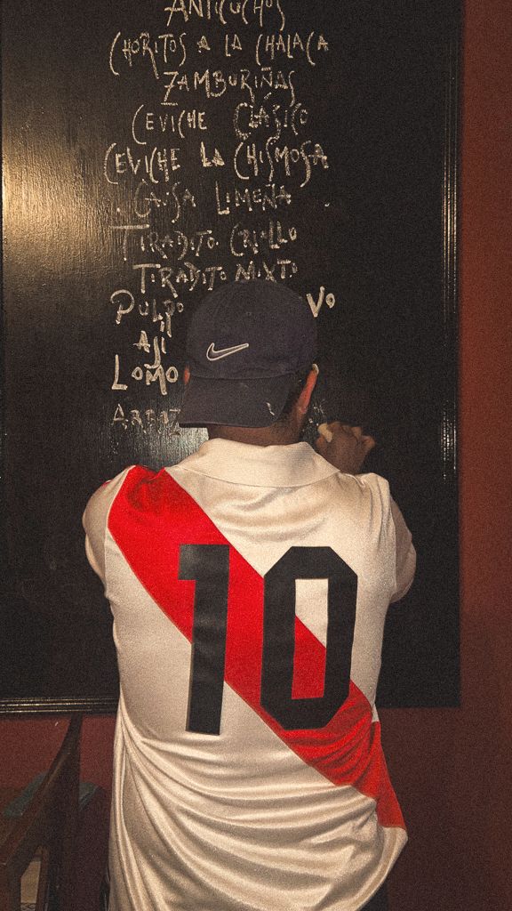 Escribiendo la carta del día en la pizarra con la camiseta de Perú