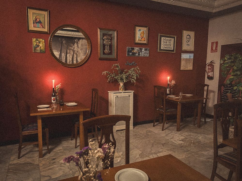 La sala con pared roja, cuadros peruanos y velas